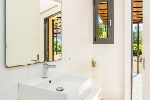 a white bathroom with a sink and mirrors at Alfonsa in Pollença