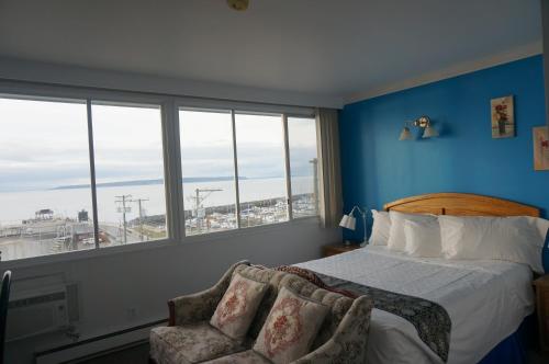 a bedroom with a bed and a chair and windows at Marine Inn in Powell River