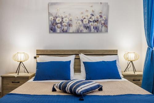 a bed with blue pillows and a painting on the wall at Dimitra's House in Glossa