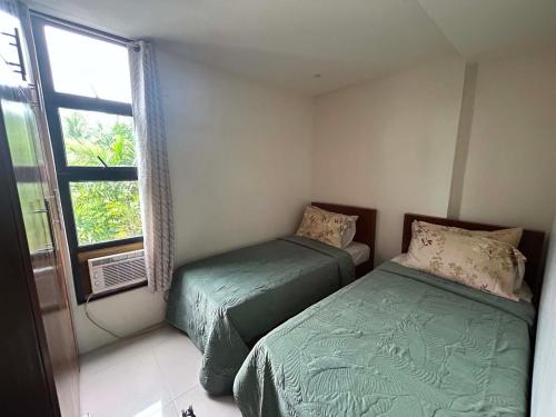 a bedroom with two beds and a window at Residencia de Azucena in Tacloban