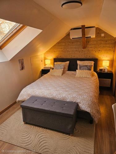 a bedroom with a large bed with a bench on it at Le passage, maisonnette cosy classée 4 étoiles in Pont-lʼÉvêque