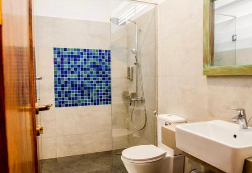a bathroom with a shower and a toilet and a sink at Linará in Hikkaduwa