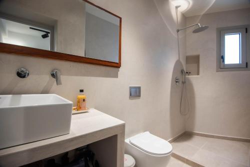 a bathroom with a sink and a toilet and a mirror at SunWave Residence in Agios Nikolaos