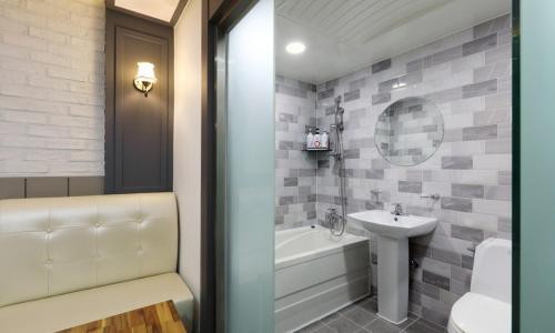 a bathroom with a sink and a tub and a toilet at Gukmin Hotel in Gumi
