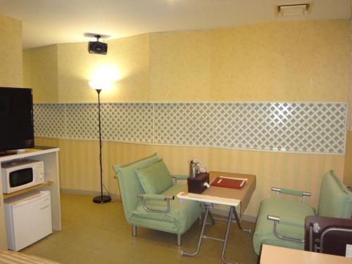 a waiting room with chairs and a table and a tv at Utility Hotel Coo in Yokoshibahikari