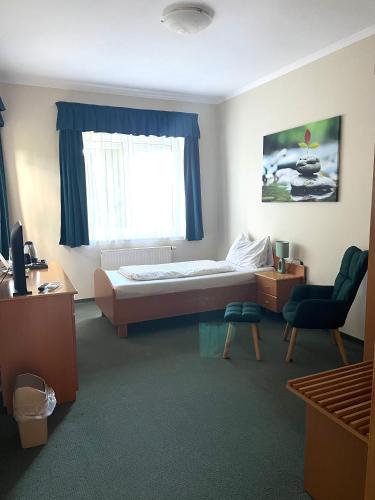 a bedroom with a bed and a window and a chair at Hotel Weldi in Győr