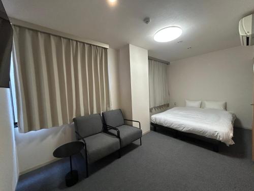 a hotel room with a bed and a chair at TOMAレジデンスホテル TOMA Residence Hotel in Kure