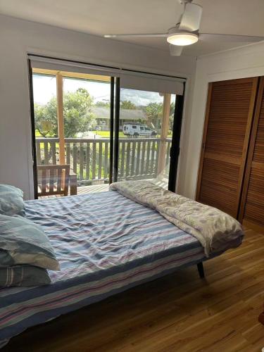 a bed in a bedroom with a balcony at Tranquil Waters Edge Escape in Sanctuary Point