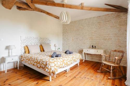 a bedroom with a bed and a table and a chair at Ambre à la Rochelle in Vergné