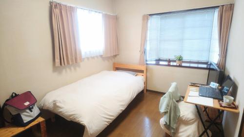 a small bedroom with a bed and a desk with a laptop at 民泊よこてこよ in Yokote