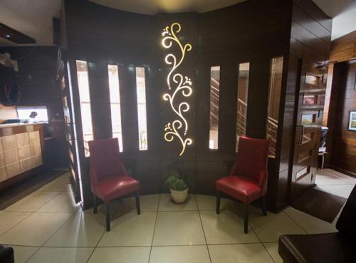 a restaurant with two red chairs and a wall with a painting at ANR Hotels in Lucknow