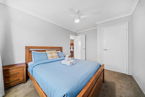 a bedroom with a blue bed with a wooden headboard at Garrison Cottage in The Vines