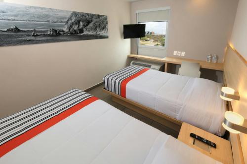 a hotel room with two beds and a window at City Express Junior by Marriott Cancun in Cancún