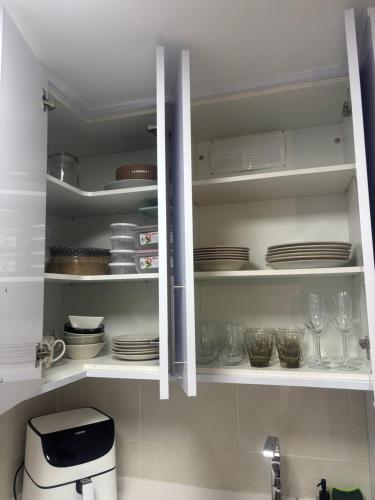 a kitchen with white cabinets with plates and dishes at Maresia in Burela de Cabo