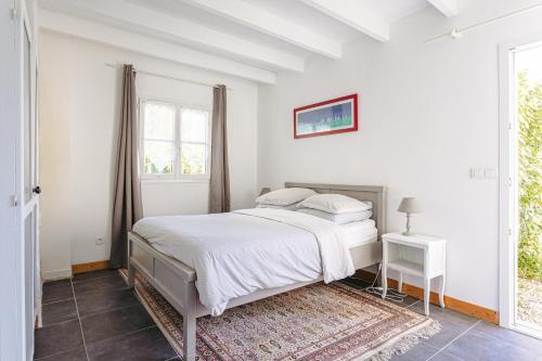 a white bedroom with a bed and a window at Gite Les Jardins d'Harmonie in Bourgneuf