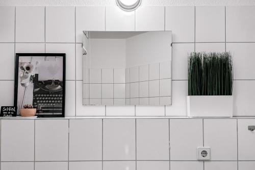 a white tiled bathroom with a mirror and plants at City Retreat Zwickau mit Balkon zum Innenhof in Zwickau