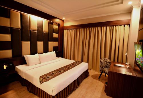 a bedroom with a large bed and a table and a desk at Angkasa Garden Hotel in Pekanbaru