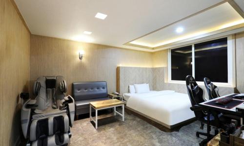 a hotel room with a bed and a desk and a bed and a chair at Gukmin Hotel in Gumi