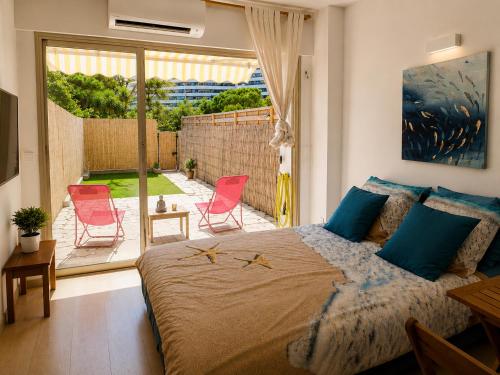 a bedroom with a bed and a patio with chairs at Studio Rez de jardin Marina baie des Anges in Villeneuve-Loubet