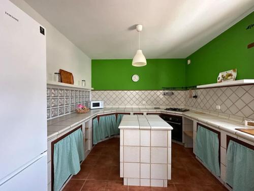 a kitchen with green walls and a white counter top at Private villa with pool in the mountains in Pájara