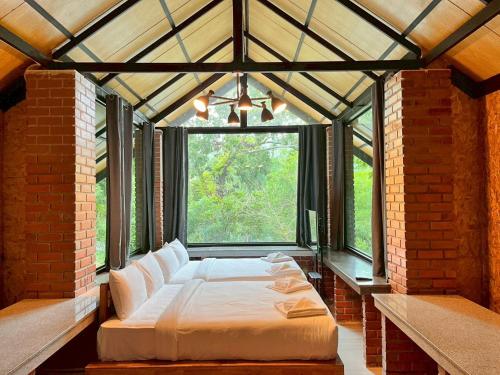 a large bed in a room with a large window at Puprai Tarnnarm Resort in Thong Pha Phum
