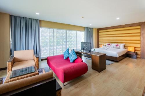 a hotel room with a bed and a red couch at The Kris Resort Hotel in Patong Beach