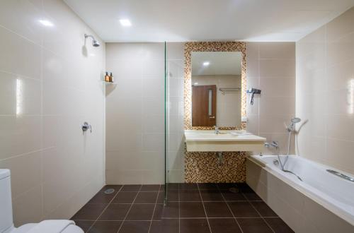 a bathroom with a tub and a sink and a mirror at The Kris Resort Hotel in Patong Beach