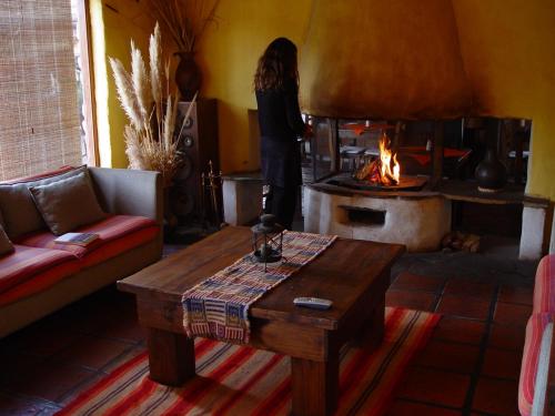 a woman standing in a living room with a fireplace at Rincón De Fuego in Tilcara