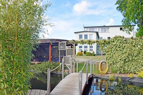 a wooden bridge over a pond in front of a house at Ferienwohnung Altefaehr mit Seebli in Altefähr