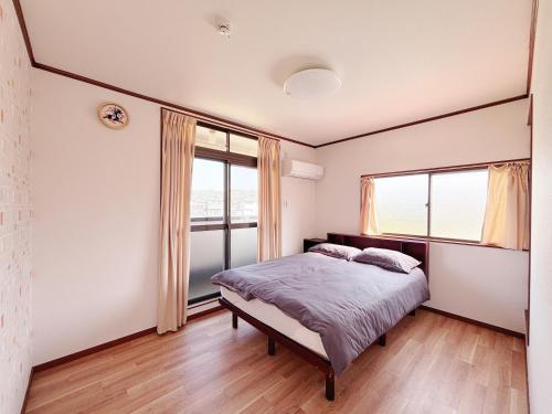a bedroom with a bed and two windows at 晴の川 in Wakayama
