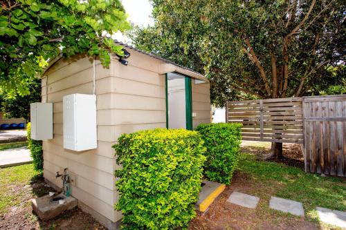 a small shed with green doors next to a fence at Tasman Holiday Parks - Hervey Bay in Hervey Bay
