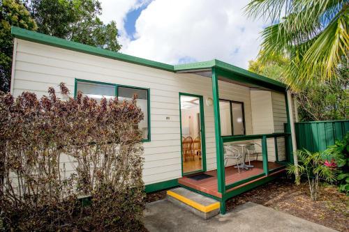 a green and white tiny house with a porch at Tasman Holiday Parks - Hervey Bay in Hervey Bay