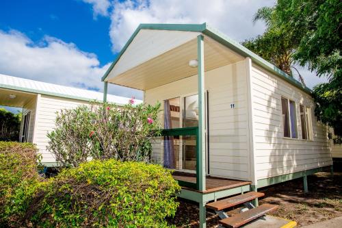 a small white tiny house with a green roof at Tasman Holiday Parks - Hervey Bay in Hervey Bay