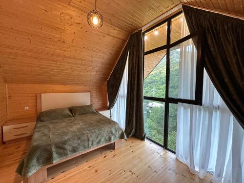 a bedroom with a bed and a large window at Iliaseuli's Cottage in K'vemo Jocho