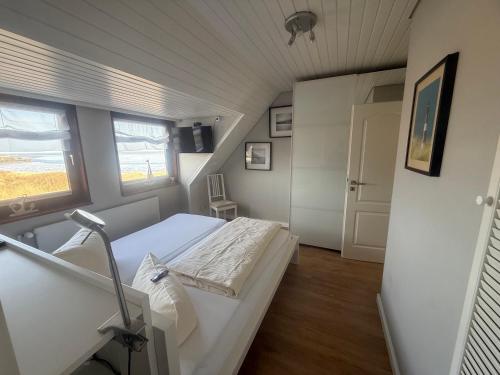 a small room with a bed and a window at Zur Mühle Munkmarsch in Sylt