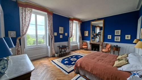 a bedroom with blue walls and a bed and a mirror at Le Château de La Coste in Saint-Julien