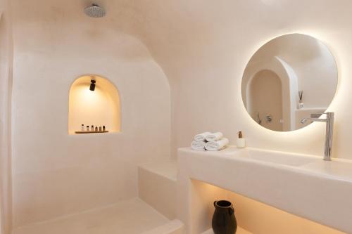 a white bathroom with a sink and a mirror at Mirabo Villas in Firostefani