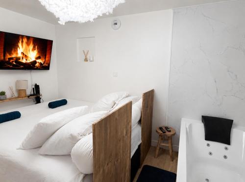 a bedroom with a bed with white pillows and a fireplace at La Cave Des Merveilles in Mâcon
