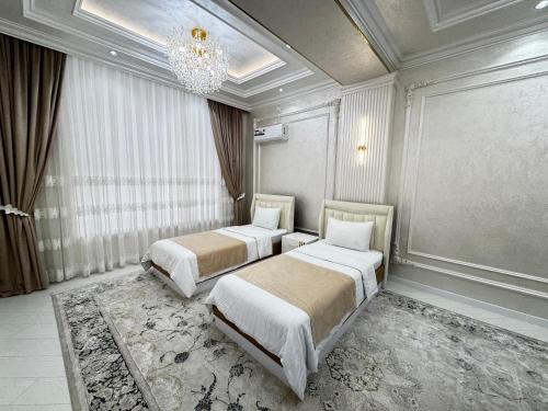 two beds in a room with a chandelier at Samarkand Premium Apartment 1 in Samarkand