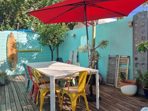 a table and chairs under a red umbrella on a deck at Ô PasSage - Kaz Auberge in Saint-Pierre