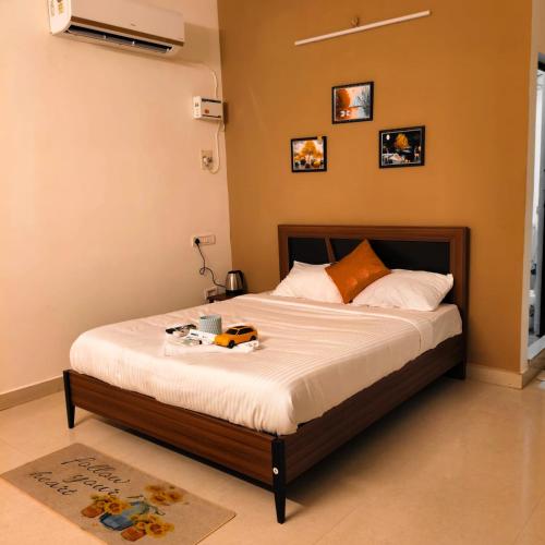 a bedroom with a bed with white sheets and orange pillows at Tamil Megam Villa in Chennai