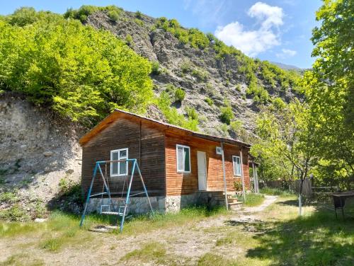 a small house with a ladder in front of a mountain at Restaran otel in İsmayıllı