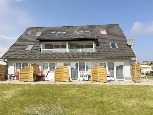 a house with four yellow chairs and a yard at Haus Inselperle mit Blick auf den Bodden in Alt Reddevitz