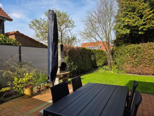 a black table with chairs and an umbrella in a backyard at Nr 64 - Ferienhaus Krabbe 12 in Carolinensiel