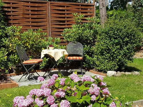 two chairs and a table in a garden with flowers at Ferienwohnung Inge Grahl in Lenz