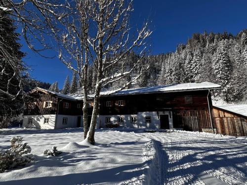 a snow covered building with a tree in front of it at Mitteralm-Kreuth in Kreuth