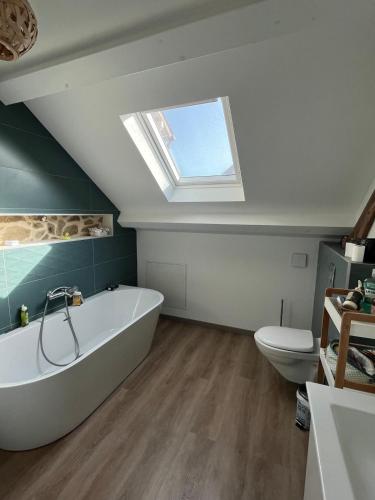 a bathroom with a tub and a toilet and a skylight at Chez Paulette - par Happy House in Gouzon
