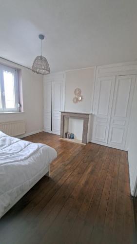 a white bedroom with a bed and a fireplace at Maison Aux Cailloux in Calais