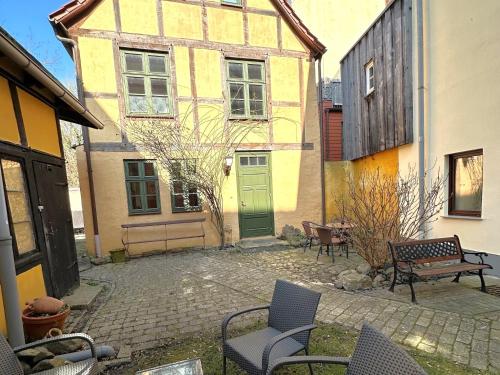 a courtyard with chairs and a green door and buildings at Altstadthaus Stralsund Külpstraße 11 in Stralsund