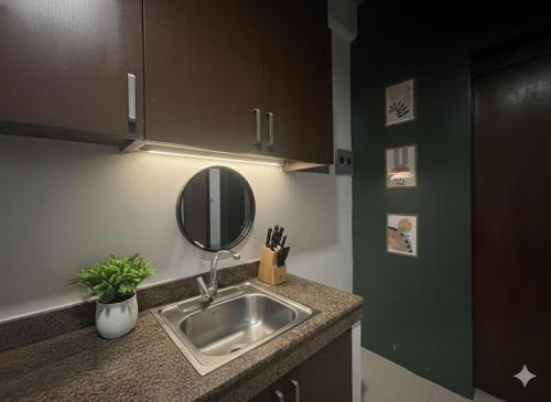 a kitchen counter with a sink and a mirror at Ortigas Uptown Bonifacio CBD Hostel in Sampong